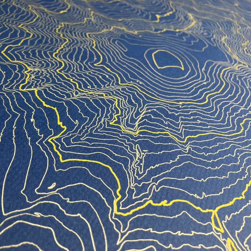 Framed pen-plotted topographic map in the navy colorway displayed in a real room, from the same series as this topographic map of Borah Peak, Idaho