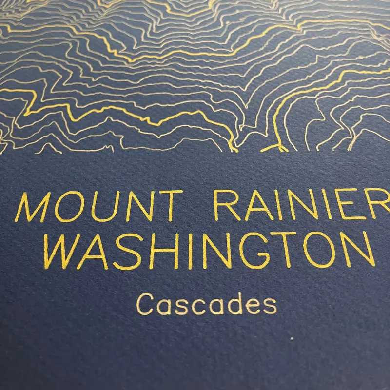 Framed pen-plotted topographic map in the navy colorway displayed in a real room, from the same series as this topographic map of Borah Peak, Idaho