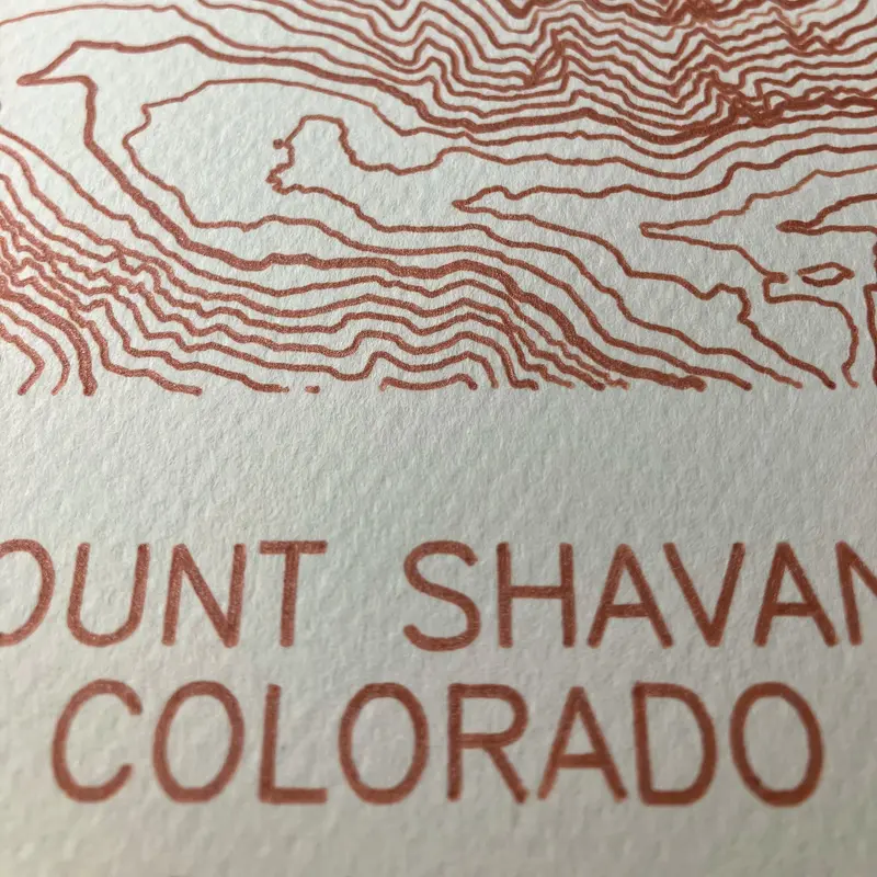 Framed pen-plotted topographic map in the cream colorway displayed in a real room, from the same series as this topographic map of Borah Peak, Idaho