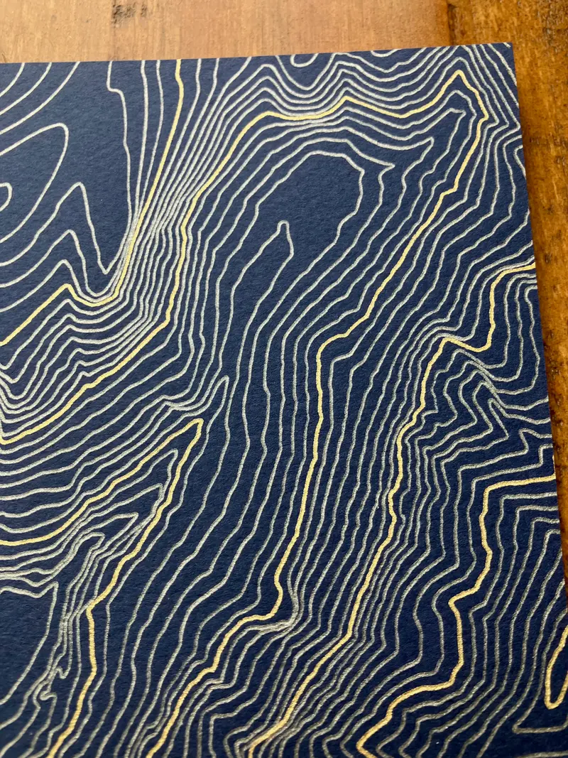 Framed pen-plotted topographic map displayed in a real room, from the same series as this topographic map of Borah Peak, Idaho
